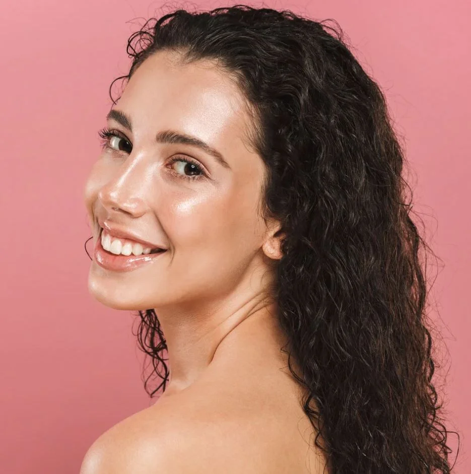A woman with curly hair showcases fuller eyebrows thanks to an eyebrow transplant